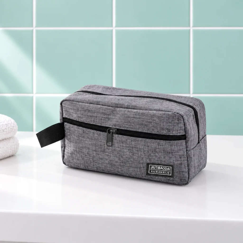 Trousse de toilette homme sport grise, fermée de trois quarts sur la tablette du lavabo